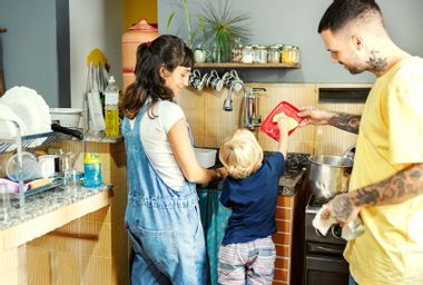 Young couple and son washing the dishes in the kitchen