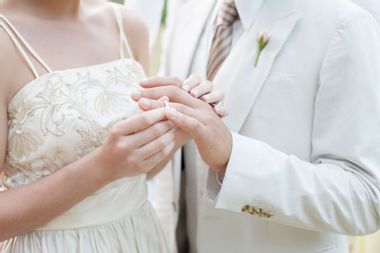 Bride putting ring on grooms finger