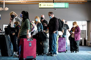 Passengers with face masks wait in line at a Frontier Airlines ticket booth inside the main terminal at Long Island MacArthur Airport, in Ronkonkoma, New York