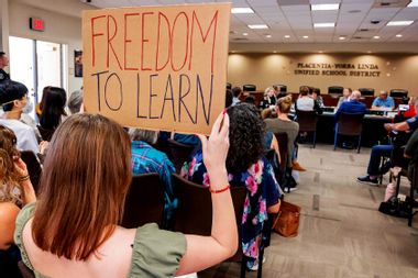 A student holds up a sign against banning CRT holds up a sign as members of the Placentia-Yorba Linda Unified School Board meeting