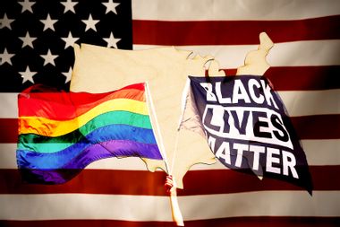 American flag, Pride Flag, BLM Flag and a wooden map of the USA