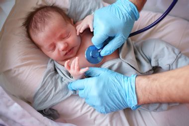 Doctor uses stethoscope to listen to baby