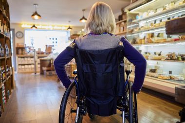 Rear View Of Woman In Wheelchair Shopping For Food
