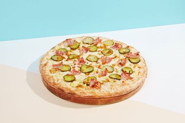 Italian pizza with bacon, pickled cucumber and crispy onion