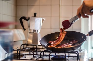 Cooking Bacon On Stove In Kitchen