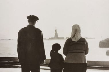 An immigrant family looking at the Statue of Liberty from Ellis Island