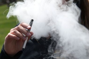 A person smokes a Juul e-cigarette