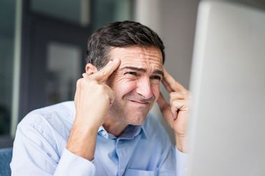 Grimacing businessman looking at computer screen