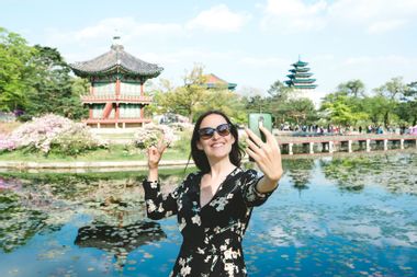 South Korea, Seoul, Woman taking a selfie with smartphone at Gyeongbokgung Palace