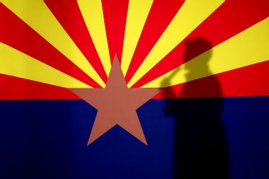 The shadow of Arizona Republican gubernatorial candidate Kari Lake is cast onto the Arizona state flag