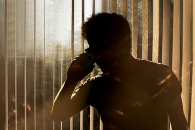 Man on a phone against window blinds