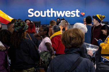 Travelers wait in line at the Southwest Airlines ticketing counter