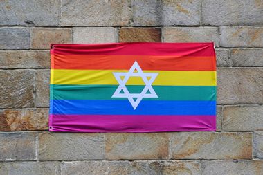 Gay pride rainbow flag with Star of David, pinned to a stone wall