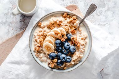 Creamy oatmeal bowl with banana, blueberries, mulberries and sesame seeds