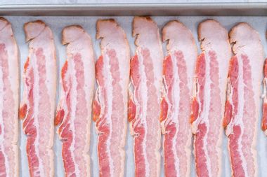 Raw bacon strips in tray ready to bake