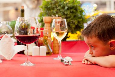 Young boy staring at glasses of red and white wine