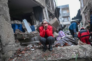 An earthquake survivor reacts as rescuers look for victims and other survivors in Hatay