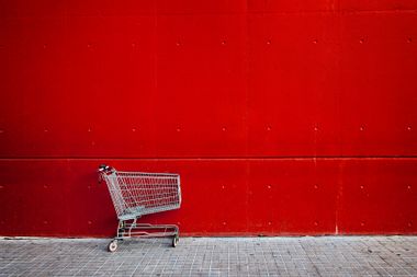Empty shopping cart in front of a red wall