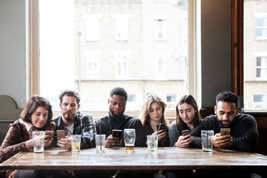 Friends at a pub all on their phones