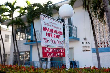 An 'Apartments for Rent' sign hangs in front of a building