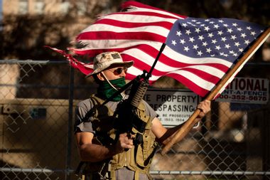 A supporter of President Trump holds a flag and gun outside the Arizona State Capitol on January 20, 2021 in Phoenix, Arizona.