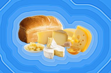 A loaf of bread, honey, and various cheeses