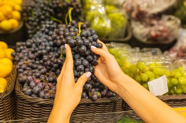 Woman choosing grapes at grocery store