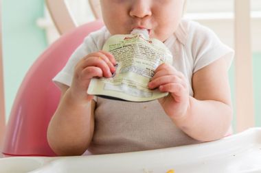 Baby girl eating apple sauce from pouch