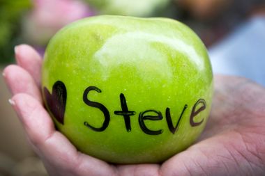 A woman holds an apple with a heart and the name of Steve Jobs written on it in front of a small memorial in his honour in San Francisco, California October 6, 2011.