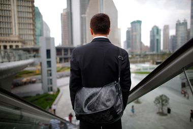 A business man rides an escalator in the financial district of Pudong in Shanghai