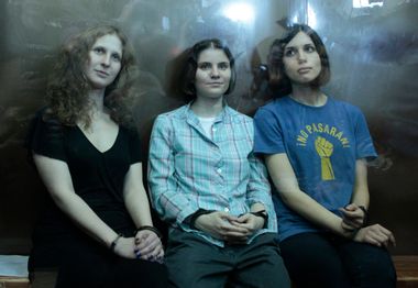 Members of the female punk band "Pussy Riot" sit in a glass-walled cage after a court hearing in Moscow