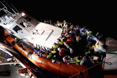 Rescued migrants stand in an Italian Coast Guard vessel after transferring from the Migrant Offshore Aid Station ship MV Phoenix between Libya and the Italian island of Lampedusa