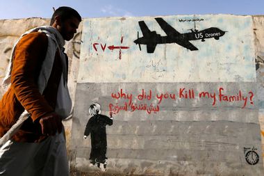 Man walks past a graffiti, denouncing strikes by U.S. drones in Yemen, painted on a wall in Sanaa