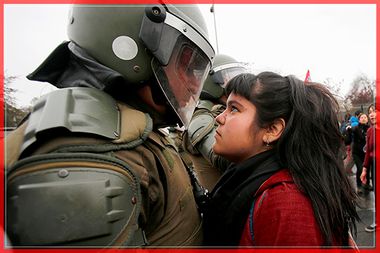 A demonstrator looks at a riot policeman during a protest marking the country's 1973 military coup in Santiago, Chile