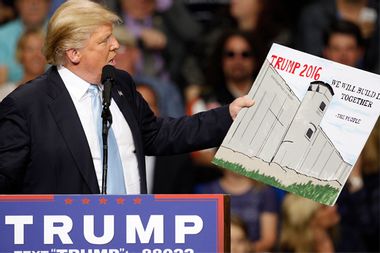 U.S. Republican presidential candidate Donald Trump holds a sign supporting his plan to build a wall between the United States and Mexico that he borrowed from a member of the audience at his campaign rally in Fayetteville North Carolina