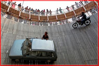 Stunt performers ride a motorcycle and a car on the walls of the "Well of Death" at the Magh Mela fair in Allahabad