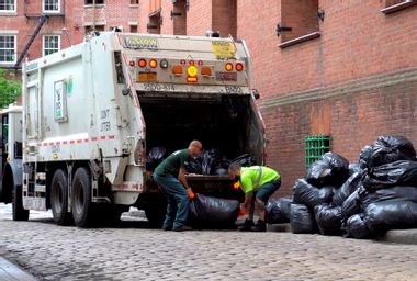Workers collect trash on a city street.