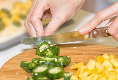 Hands cutting jalapeno, pineapple
