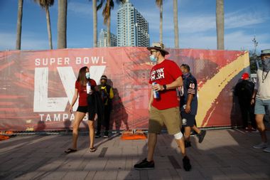 Locals walking around Tampa wearing masks in front of a Super Bowl LV sign