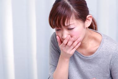 Young woman looking nauseous with hand over mouth
