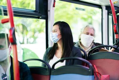 Woman wearing protective mask sitting in bus