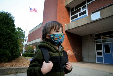 A boy arrives for the first day of school wearing a face mask