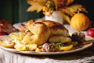 Baked chicken with potatoes and lemons on big ceramic dish