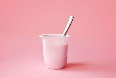 Strawberry yogurt or pudding in plastic cup on pink background