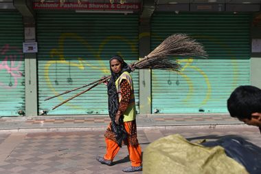 A street sweeper walks on a sidewalk in New Delhi