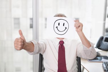 Businessman holding picture of happy face