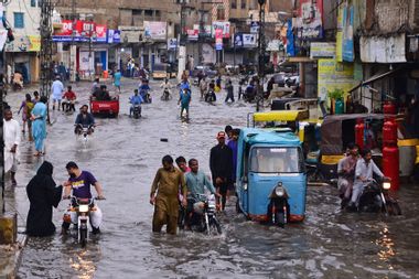 Commuters make their way through a flooded street during monsoon rainfall in Hyderabad on July 24, 2022