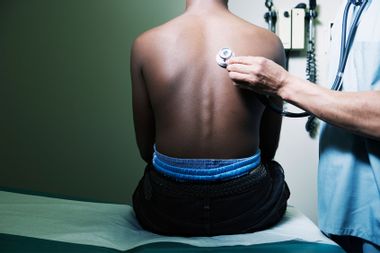 Doctor examining boy with stethoscope
