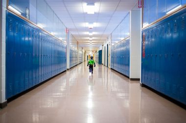 Rear view of boy running in school corridor