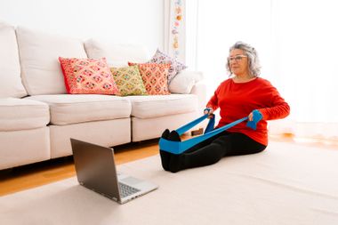 Woman doing home workout while watching tutorial on laptop